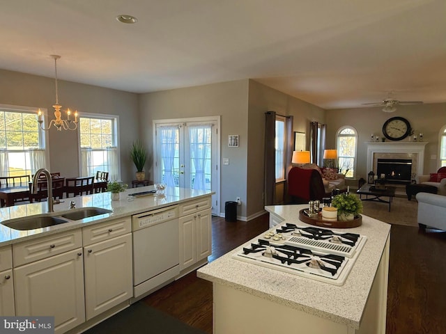 kitchen with pendant lighting, sink, white appliances, a kitchen island with sink, and white cabinets