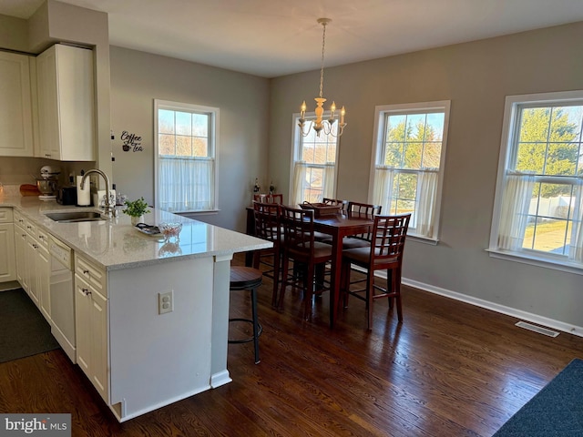 kitchen featuring dark hardwood / wood-style floors, decorative light fixtures, white cabinetry, sink, and light stone countertops