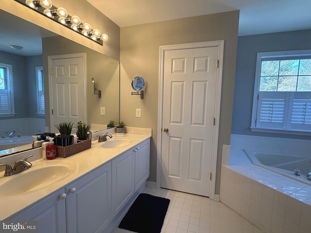 bathroom with vanity, a healthy amount of sunlight, a relaxing tiled tub, and tile patterned floors