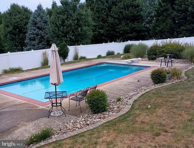 view of pool with a lawn and a diving board