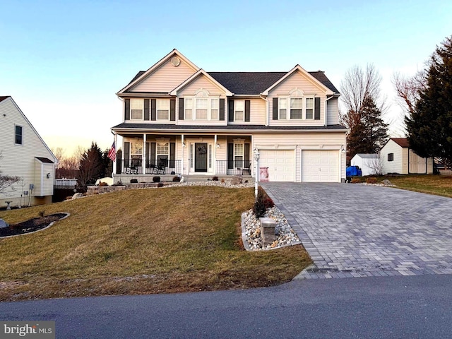 view of front facade with a garage, covered porch, and a lawn