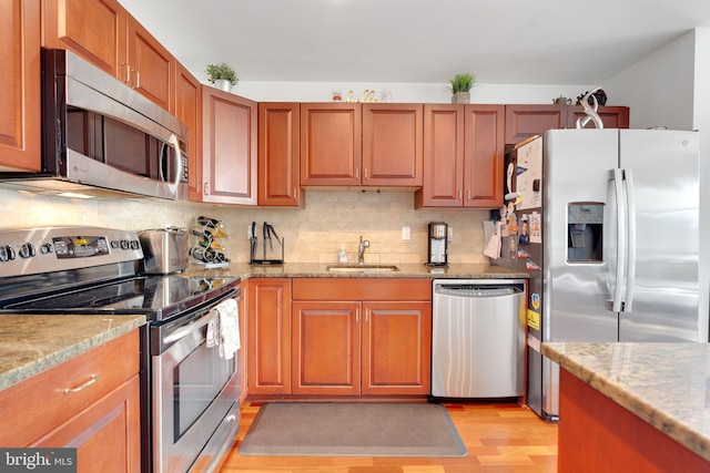 kitchen with sink, tasteful backsplash, light hardwood / wood-style flooring, stainless steel appliances, and light stone countertops