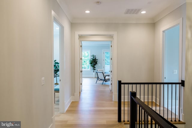 hall featuring light wood-type flooring, visible vents, an upstairs landing, and baseboards