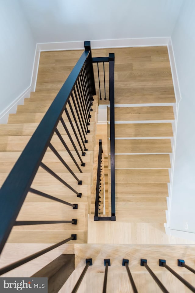 staircase featuring wood finished floors and baseboards