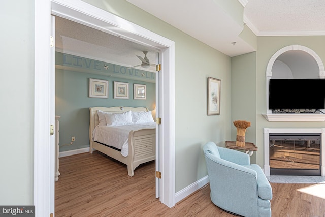 bedroom with ornamental molding, a textured ceiling, and light hardwood / wood-style floors