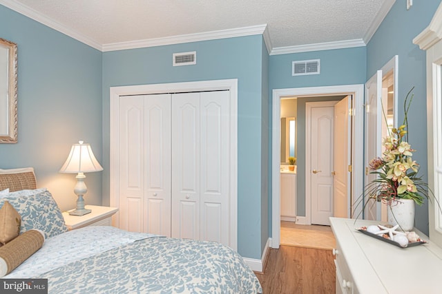 bedroom featuring ornamental molding, light hardwood / wood-style floors, a closet, and a textured ceiling