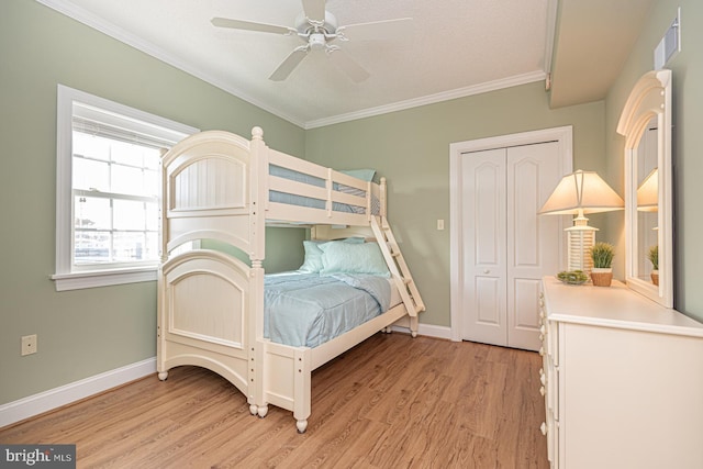 bedroom with crown molding, ceiling fan, a closet, and light wood-type flooring