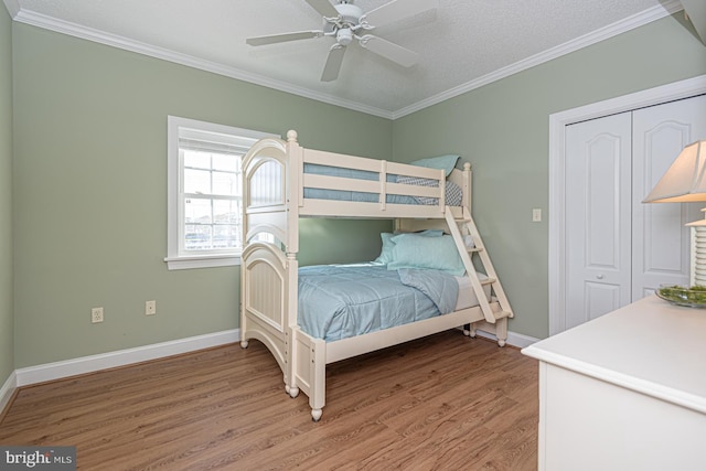 bedroom with ceiling fan, ornamental molding, hardwood / wood-style floors, and a closet