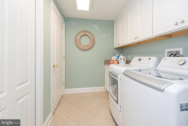 laundry area featuring light tile patterned flooring, cabinets, and washer and clothes dryer