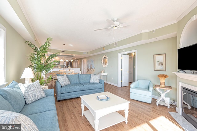 living room with ornamental molding, ceiling fan, and light hardwood / wood-style floors