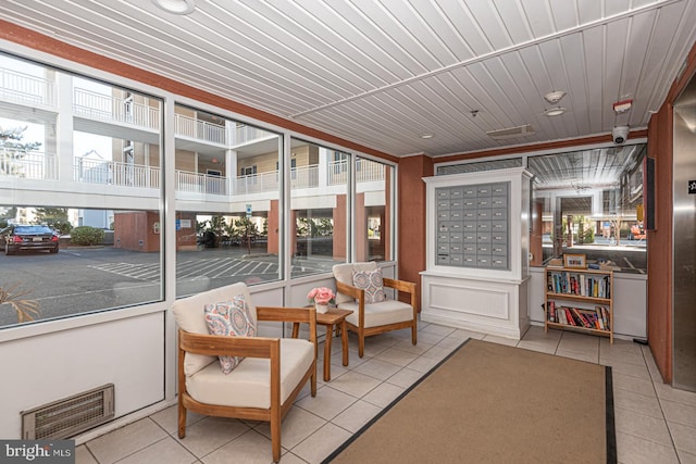 sunroom featuring a mail area, a wealth of natural light, and wooden ceiling