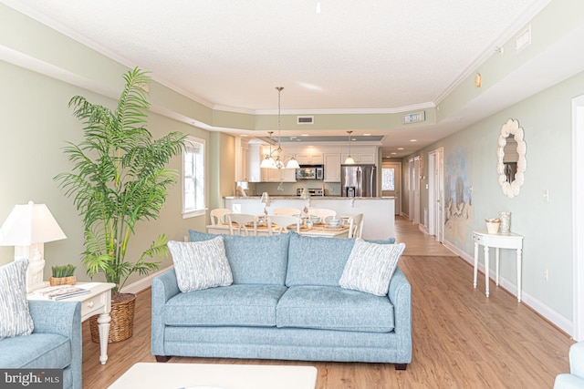 living room with ornamental molding, a textured ceiling, and light wood-type flooring