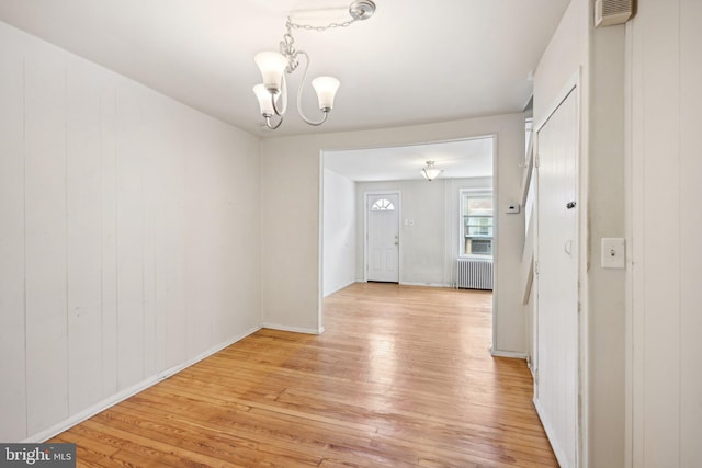 interior space featuring an inviting chandelier, radiator heating unit, and light wood-type flooring