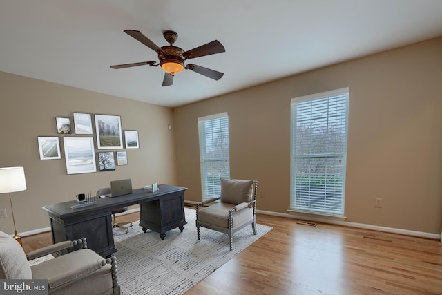 home office with light hardwood / wood-style flooring and ceiling fan