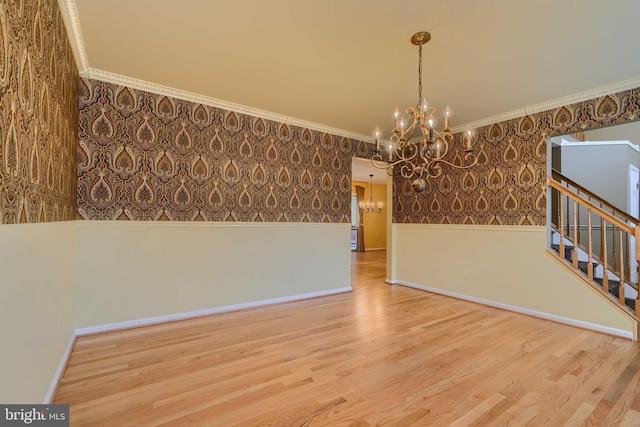 unfurnished dining area featuring hardwood / wood-style flooring, ornamental molding, and a notable chandelier