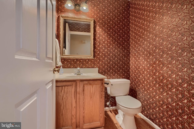 bathroom with hardwood / wood-style flooring, vanity, and toilet