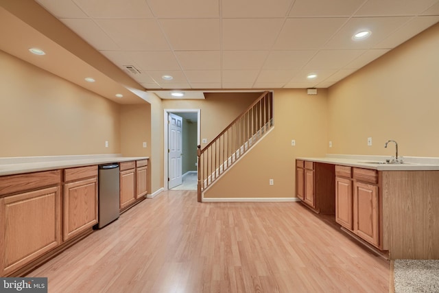 kitchen with sink, light hardwood / wood-style flooring, and a paneled ceiling