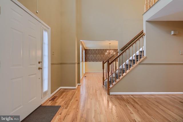 entrance foyer featuring an inviting chandelier, light wood-type flooring, and a high ceiling