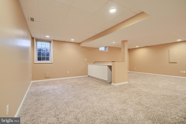 basement featuring light carpet and a drop ceiling