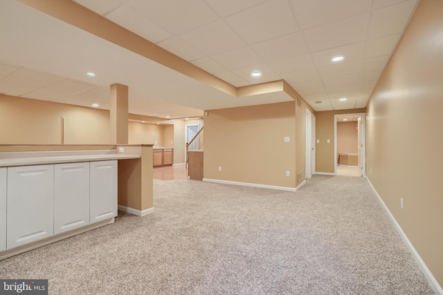 basement featuring light colored carpet and a paneled ceiling