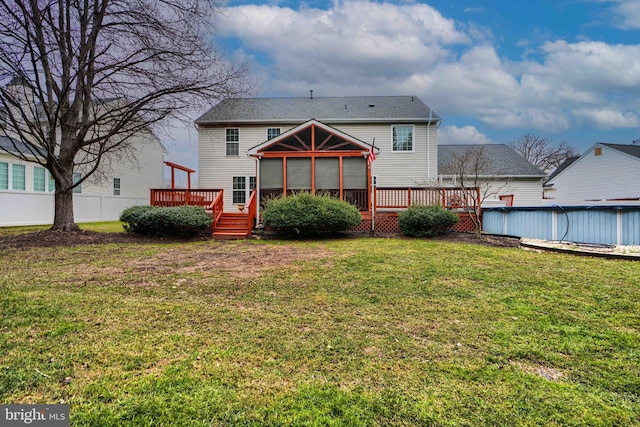 rear view of house with a sunroom, a deck, and a lawn