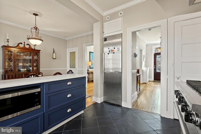 kitchen with built in appliances, blue cabinets, light countertops, crown molding, and dark tile patterned floors