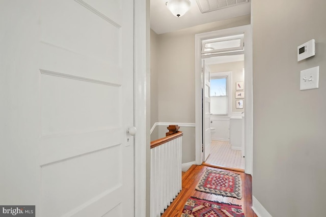 hallway featuring light wood-style floors, visible vents, and baseboards