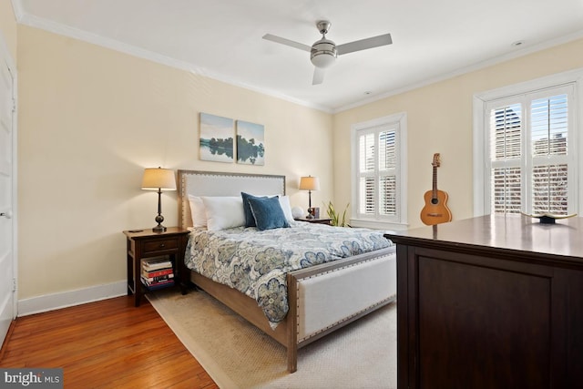 bedroom featuring ornamental molding, light wood-type flooring, baseboards, and a ceiling fan