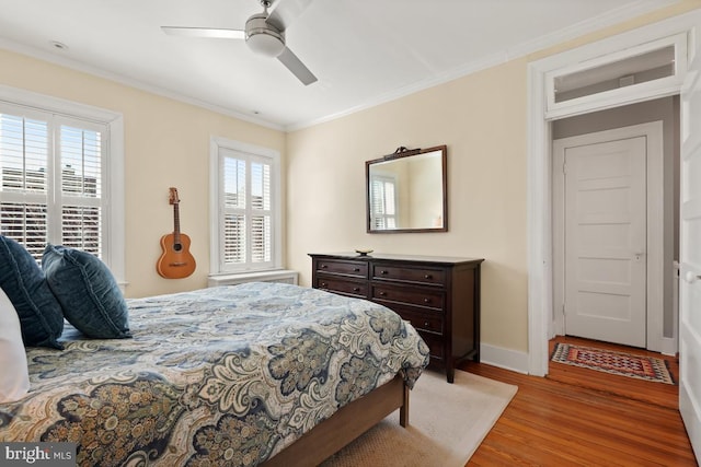 bedroom featuring a ceiling fan, baseboards, ornamental molding, and wood finished floors