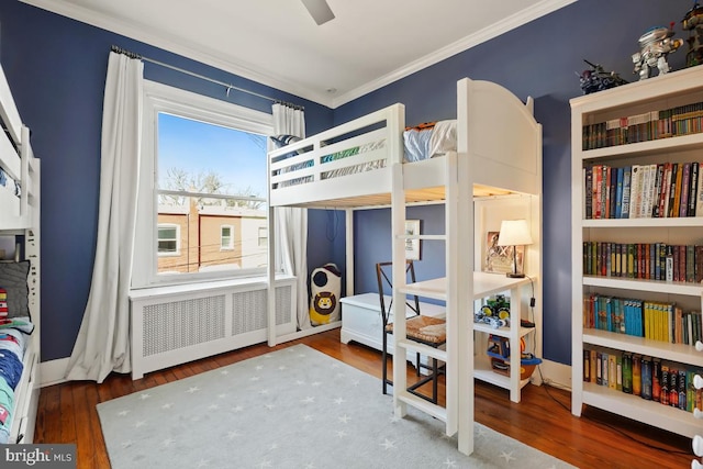 bedroom with radiator, baseboards, ornamental molding, and wood finished floors