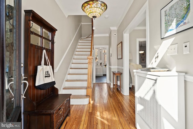 entrance foyer with light wood-style floors, baseboards, stairway, and ornamental molding