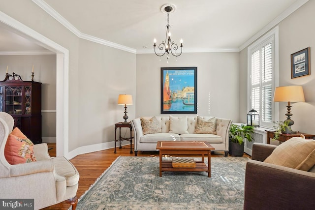 living room featuring a chandelier, ornamental molding, wood finished floors, and baseboards