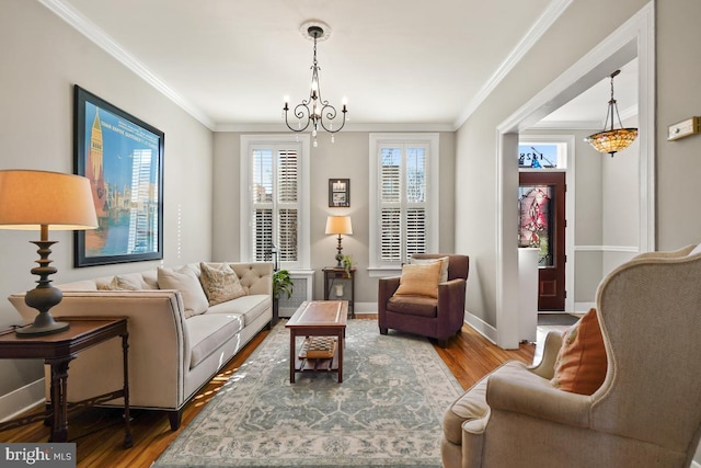 sitting room featuring ornamental molding, a chandelier, baseboards, and wood finished floors