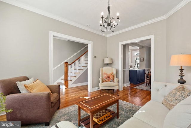 living area featuring stairs, a chandelier, crown molding, and wood finished floors