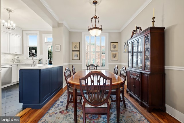 dining space featuring dark wood-type flooring, crown molding, and baseboards