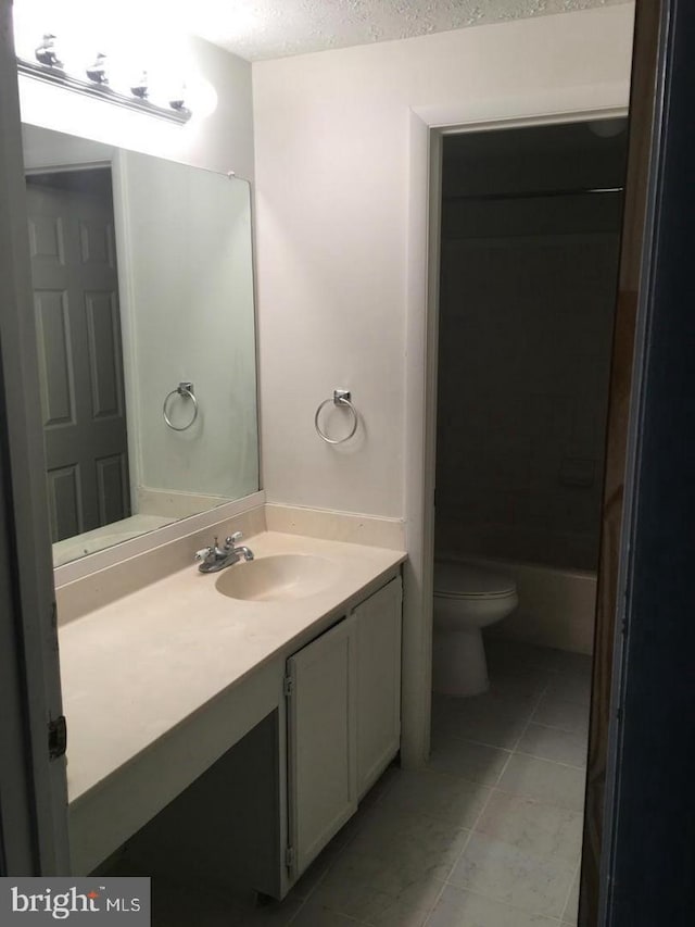 bathroom featuring vanity, tile patterned flooring, toilet, and a textured ceiling