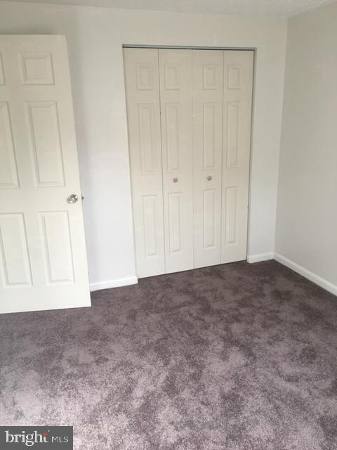 unfurnished bedroom with a closet and dark colored carpet