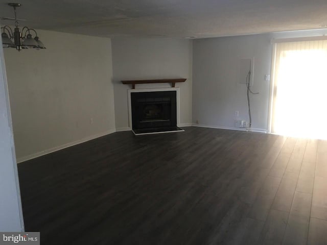 unfurnished living room featuring a notable chandelier and dark hardwood / wood-style floors