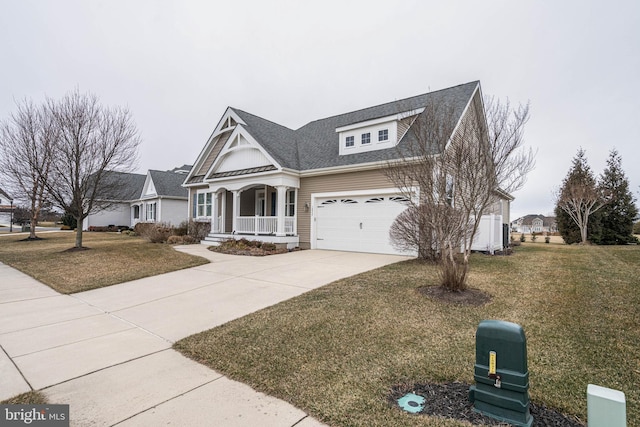 view of front of property with covered porch, driveway, a front yard, and a garage