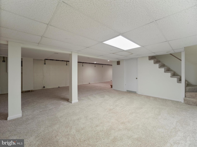 basement featuring a drop ceiling and light colored carpet