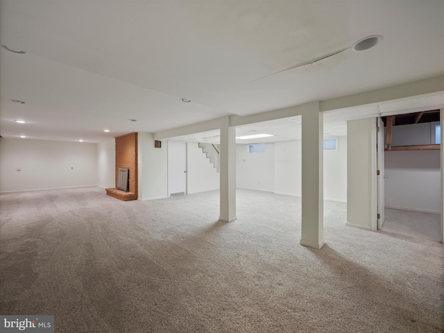 basement featuring a brick fireplace and light colored carpet