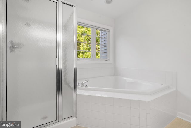 bathroom with a garden tub, a shower stall, and wood finished floors