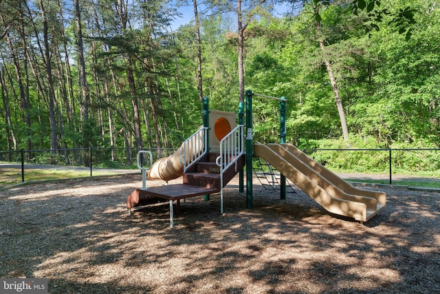 community jungle gym featuring fence and a wooded view