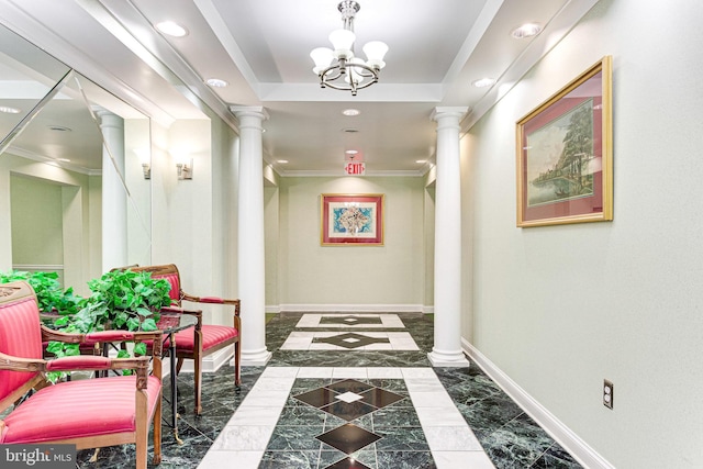 hallway featuring a notable chandelier, ornamental molding, a raised ceiling, and ornate columns