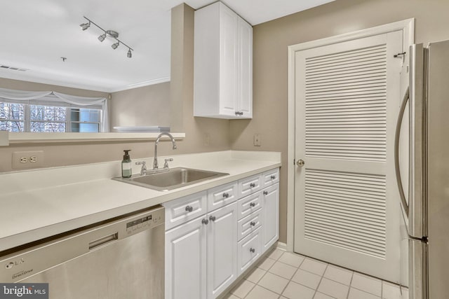 kitchen featuring sink, light tile patterned floors, rail lighting, appliances with stainless steel finishes, and white cabinetry