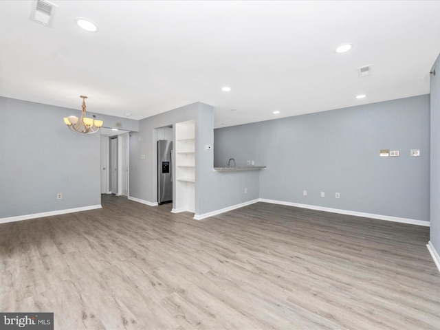 unfurnished living room featuring a notable chandelier and hardwood / wood-style flooring