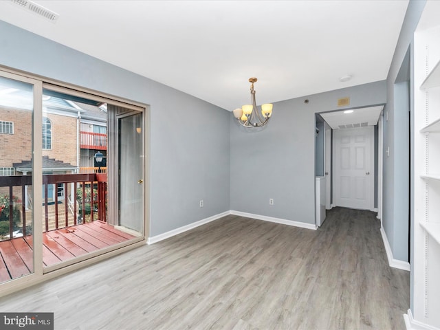 unfurnished room with an inviting chandelier, hardwood / wood-style floors, and a healthy amount of sunlight