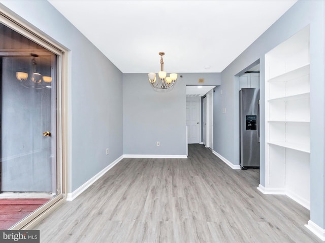 unfurnished dining area featuring a chandelier and light wood-type flooring