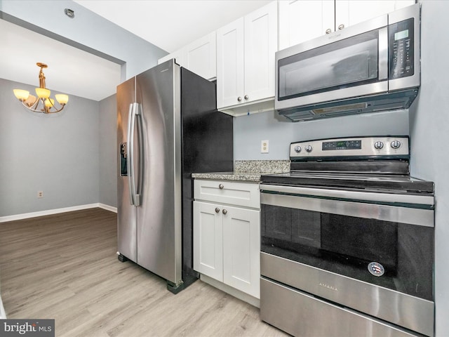 kitchen with light stone counters, light wood-type flooring, white cabinets, and appliances with stainless steel finishes