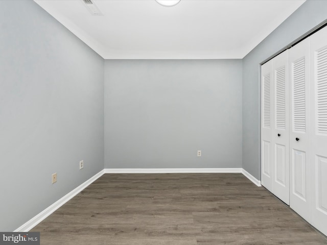 unfurnished bedroom featuring dark wood-type flooring and a closet